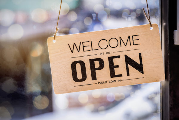 Sign hanging on the front of a convenience store saying we are open.