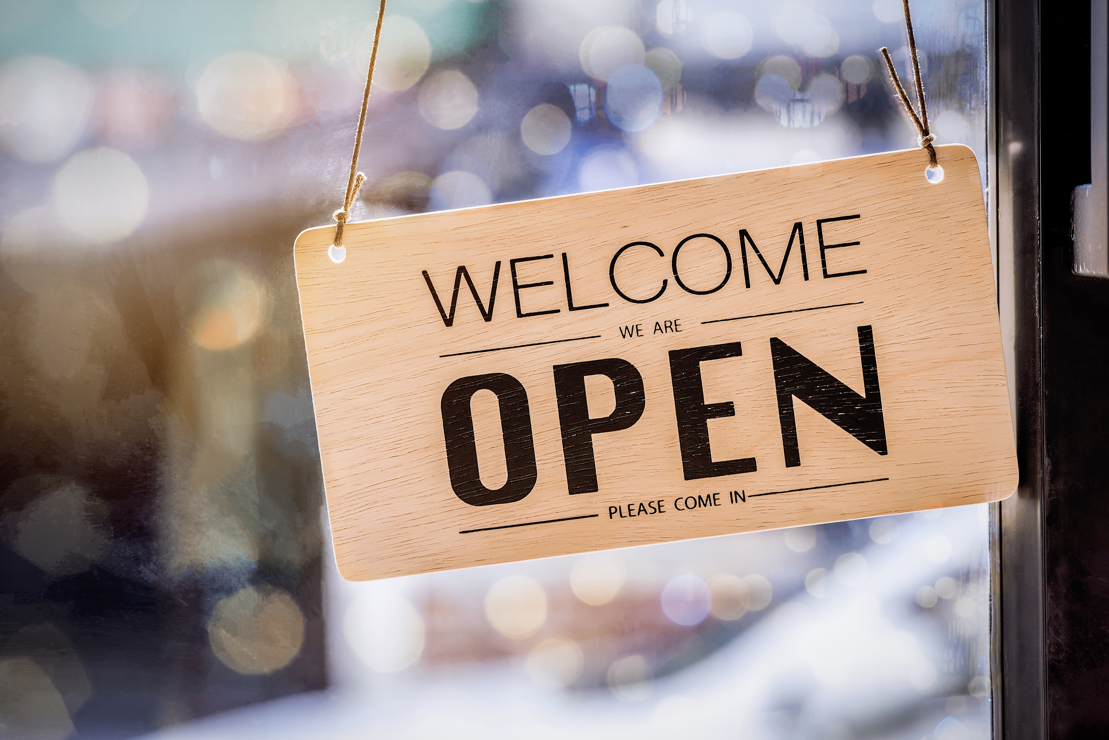 Sign hanging on the front of a convenience store saying we are open.