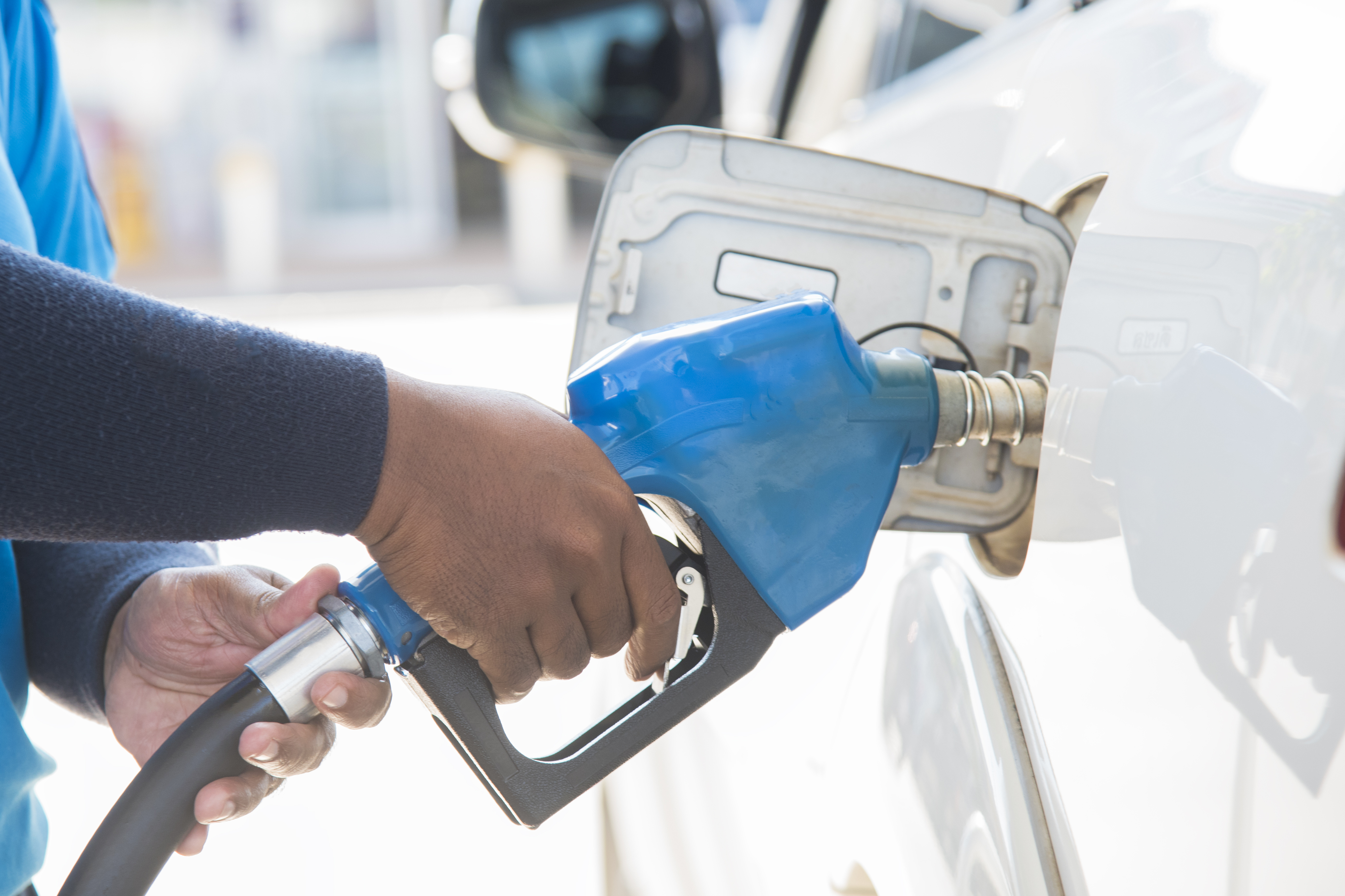 Person filling up car with fuel at a gas station.