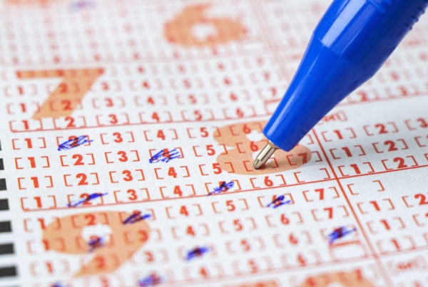 Up close shot of person filling out a lottery ticket with a pen.