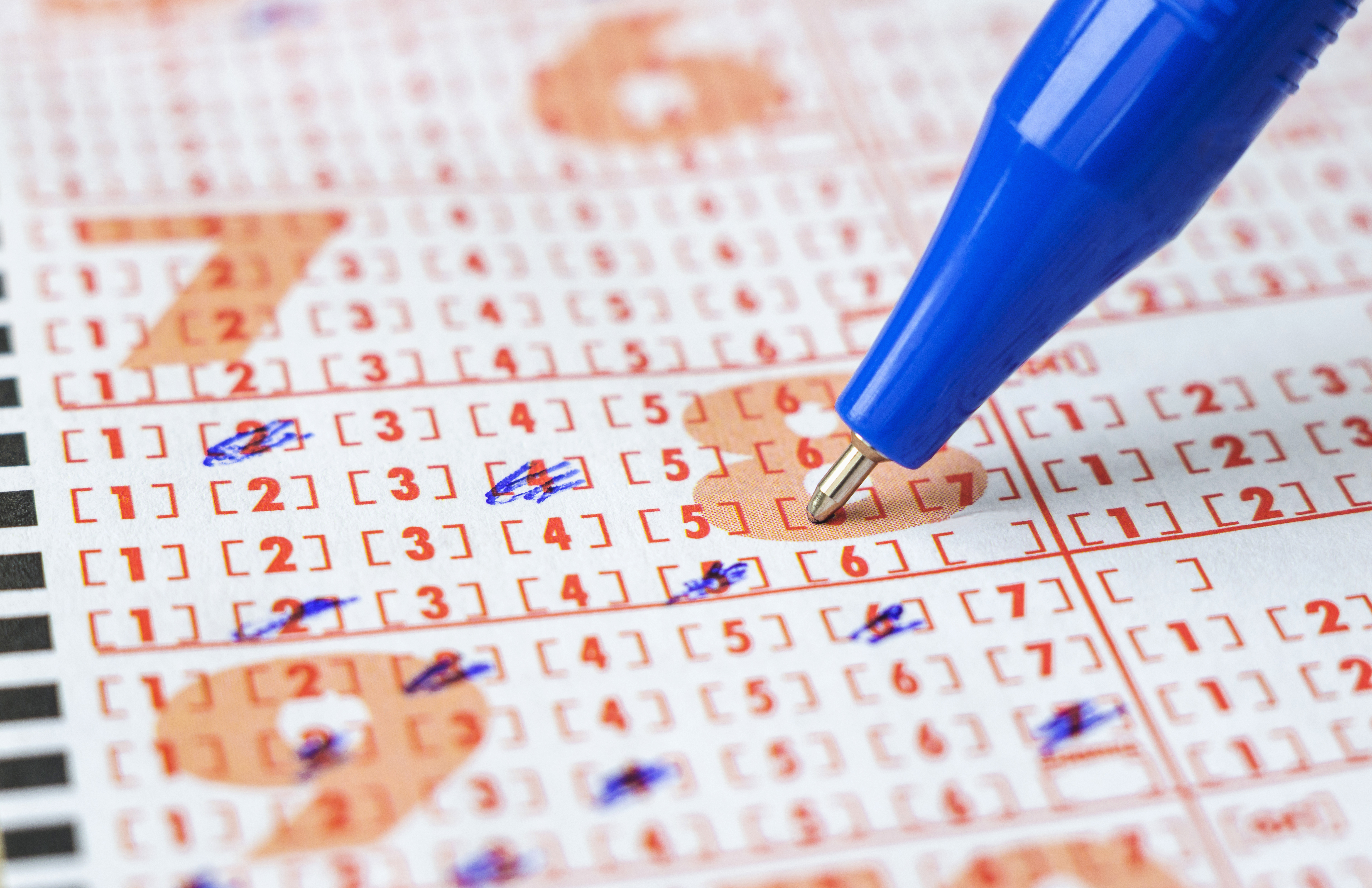 Up close shot of person filling out a lottery ticket with a pen.